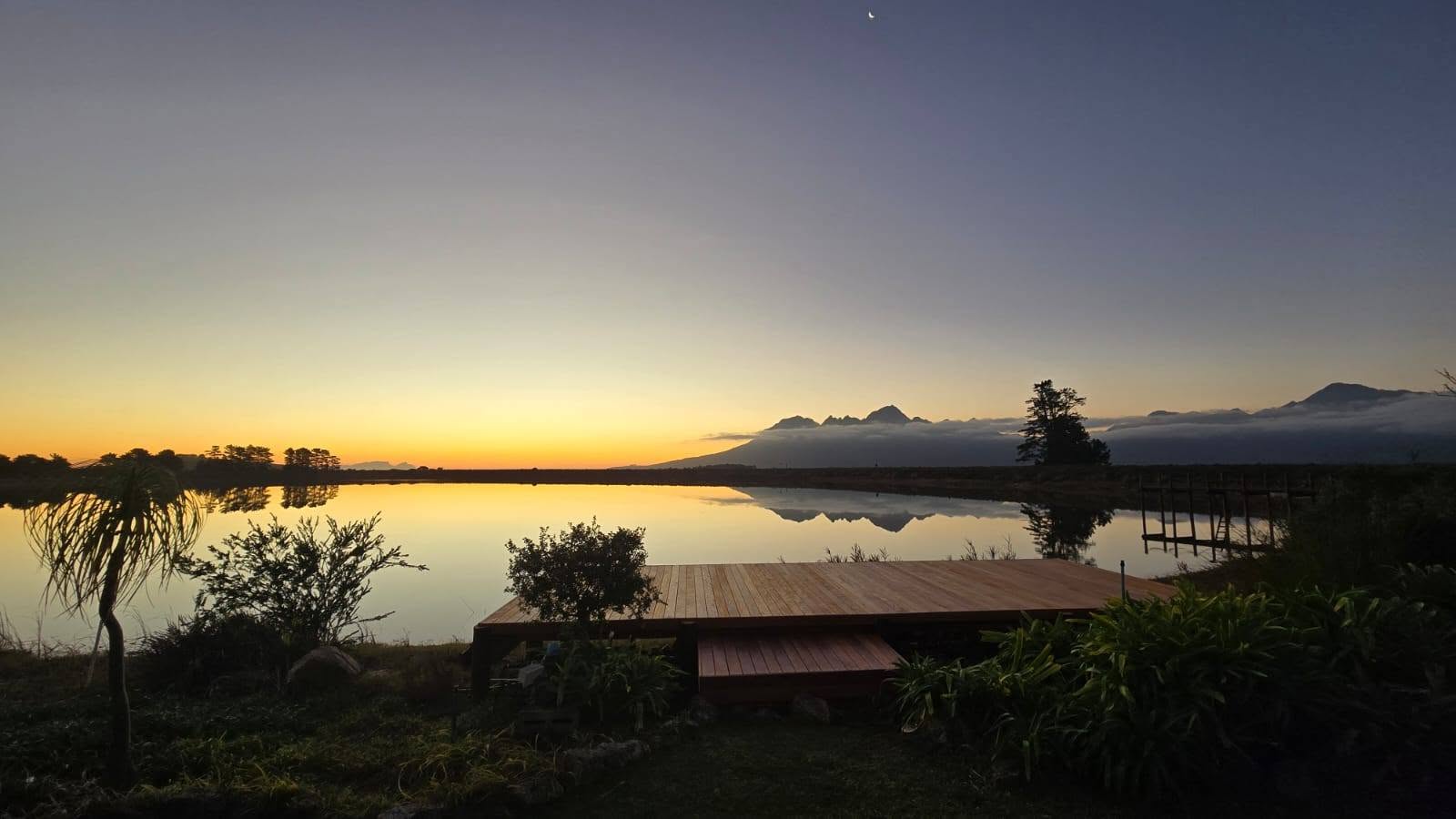 Timber deck at the water with the mountains at sunset